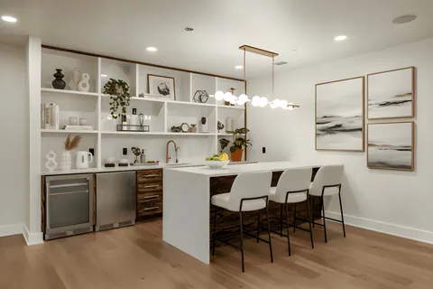 Lower-level wet bar with open shelving and seating