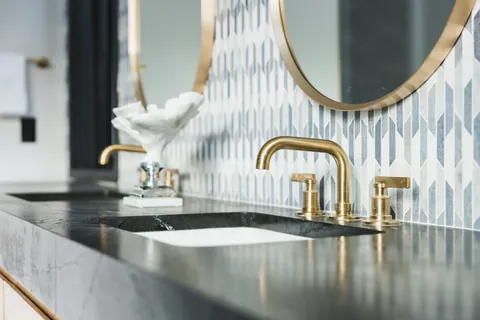 Vanity with brass faucets and patterned tile