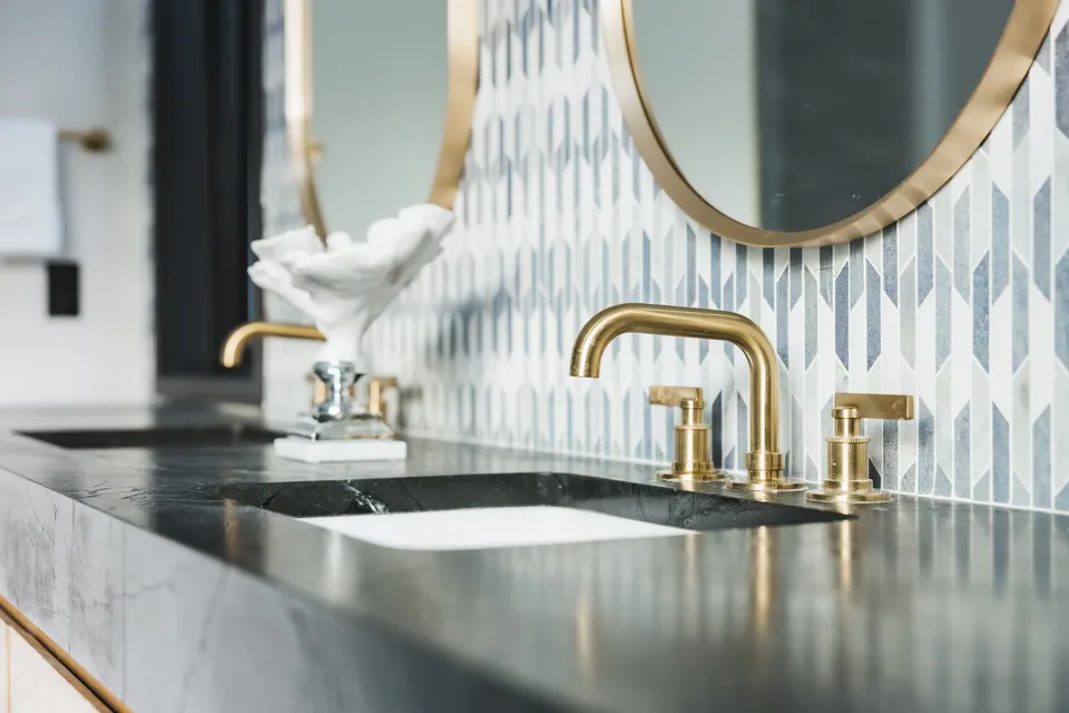 Vanity with brass faucets and patterned tile