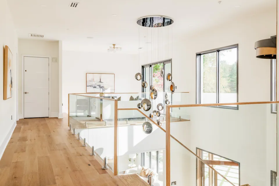 Upper hallway with glass railing and sculptural chandelier